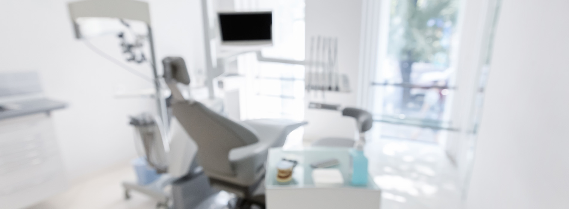 The image shows a modern dental clinic interior with various pieces of equipment, including a dental chair and an X-ray machine.