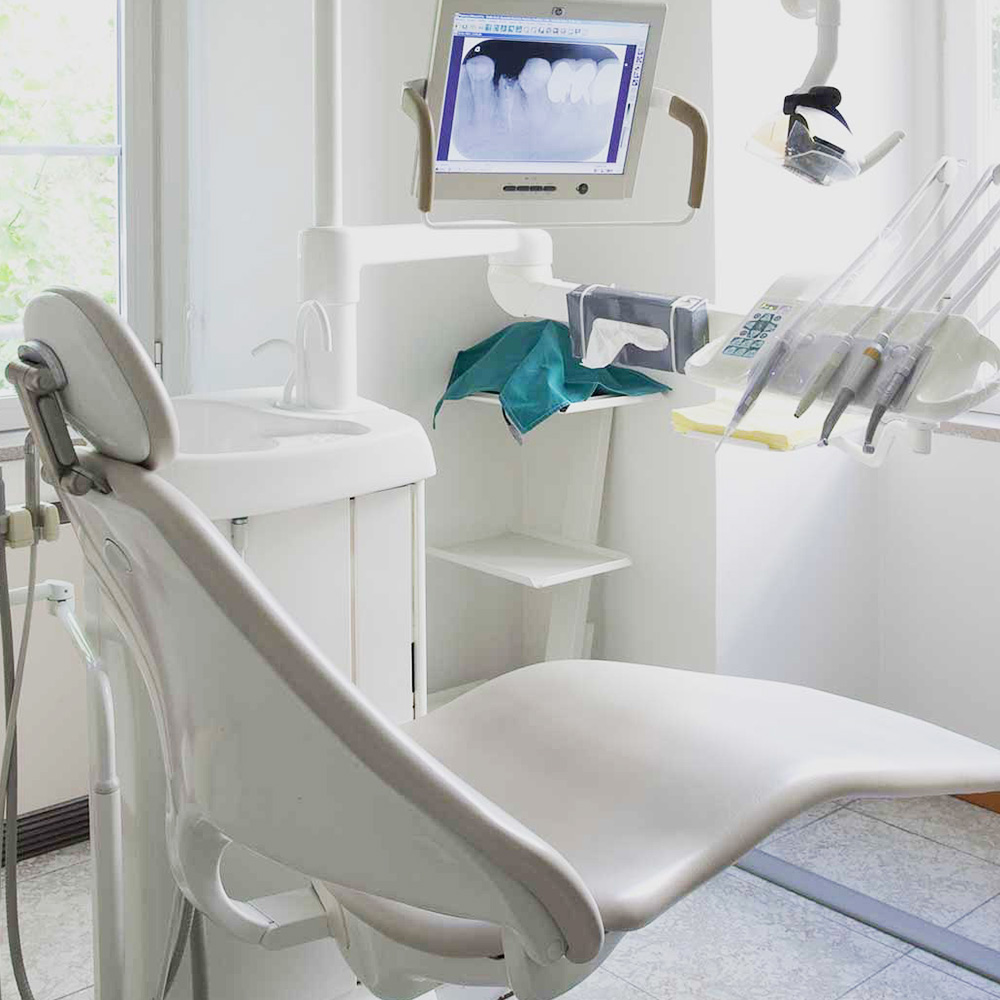 The image shows a dental office interior with a dental chair, a dental light, and various dental equipment.